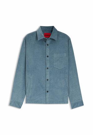 Corduroy overhemd in lichtblauw met een knoopsluiting aan de voorkant, een spreidkraag, een borstzak en twee zijzakken. Zwarte knopen en een geribbelde textuur.