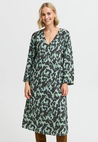 Rochie cu mânecă lungă, în imprimeu leopard negru și verde mentă, cu decolteu în V și o croială lejeră, realizată dintr-un material texturat.