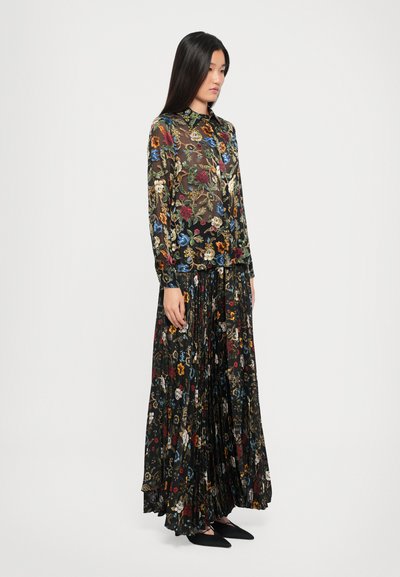 Zwart bloemenjurk set met een transparante top, voorzien van kleurrijke bloemenpatronen, een geplooide rok en lange mouwen. Aangevuld met een kraag.