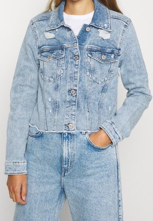 Světle modrá džínsová bunda s cropped designem, se sepranými detaily, dvěma náprsními kapsami a knoflíkovým zapínáním. Obsahuje roztrhané okraje dolního lemu a manžet.