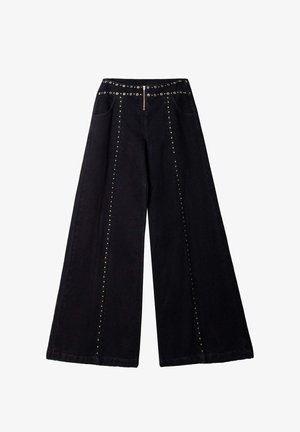 Pantalon noir à jambes larges en denim, ornés de clous métalliques le long des coutures latérales et d'une ceinture cloutée avec une fermeture éclair à l'avant et des poches.