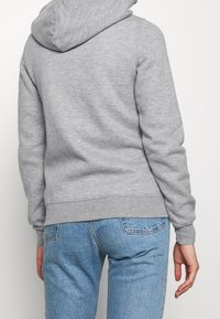 Grå huvtröja med mjukt material, ribbade ärmslut och nederkant. Kombineras med ljusblå denimjeans som har en avslappnad passform.