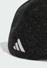 Černá vlněná čepice s texturovaným povrchem. Má bílé logo se třemi pruhy na jedné straně, zakřivený tvar a měkký materiál.