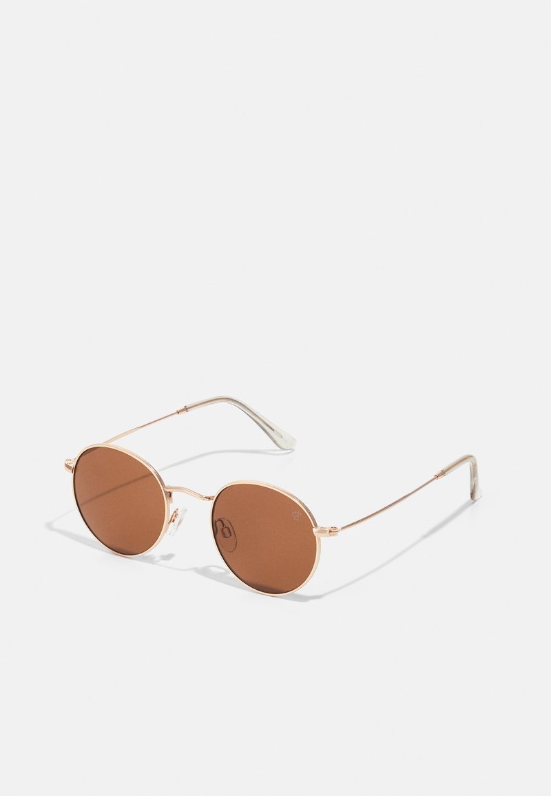 Ochelari de soare rotunzi cu lentile maronii, ramă subțire din metal auriu și accente argintii. Prezintă un design elegant și minimalist și pernuțe ajustabile pentru nas.