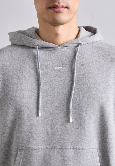 Sweatshirt à capuche gris avec une poche avant, un cordon de serrage au cou et des embouts argentés. Présente un logo de marque subtil en blanc sur la poitrine.