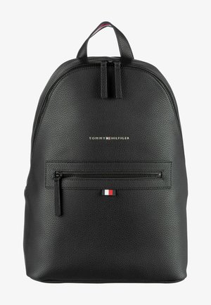 Black textured leather backpack with a top handle, front zipper pocket, and logo detailing. Accented by a small tri-color emblem.