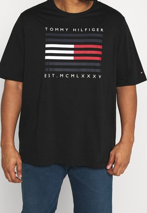 Schwarzes T-Shirt mit kurzen Ärmeln und einem grafischen Design, das horizontale Streifen in Rot, Weiß und Marineblau zeigt. Der Text "TOMMY HILFIGER" ist enthalten.