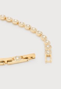 Χρυσό βραχιόλι με στρογγυλά διάφανα κρυσταλλάκια τοποθετημένα σε κυκλικούς κρίκους, με κούμπωμα που διπλώνει, σε λευκό φόντο.