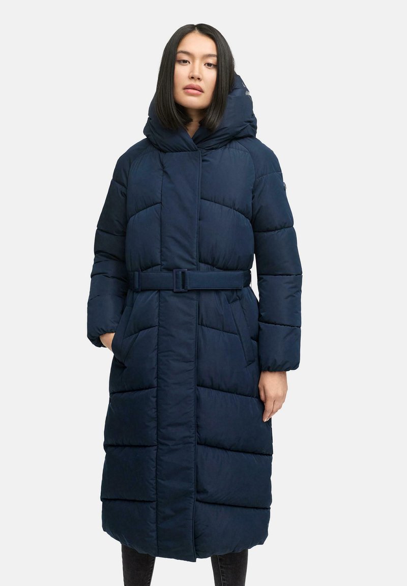 Mørkeblå pufferjakke med indsnævretTalje, oversize hætte og skrå sømdesign. Har to frontlommer og lukning foran.