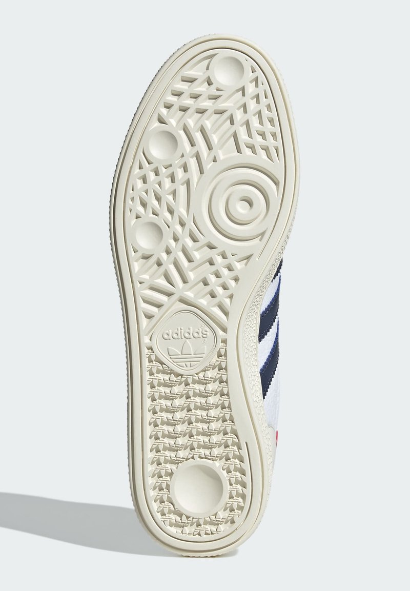 Biała podeszwa sneakersów z teksturowanej gumy, z okrągłymi i geometrycznymi wzorami. Wytłoczone logo Adidas na środku.