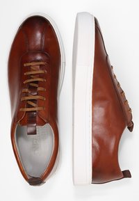 Braune Ledersneaker mit weißen Gummi-Sohlen, mit abgerundetem Zehenbereich, kontrastierenden Schnürsenkeln und dezenten Stickdetails.