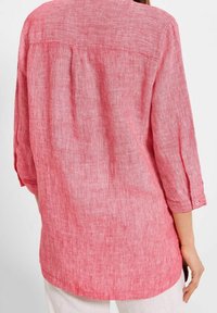 Rood-witte gestreepte shirt met driekwartmouwen, een licht losse pasvorm en een achterkant met een plooie. Gemaakt van een lichte, gestructureerde stof.