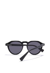 Čierne slnečné okuliare s okrúhlymi šošovkami a oktagónovým rámom. Medzi vlastnosti patrí matný povrch, logo na stranici a jedinečný dizajn mostíka.