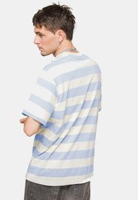 Camiseta de rayas en azul claro y crema, hecha de algodón, con un corte holgado, mangas cortas y un escote redondo.
