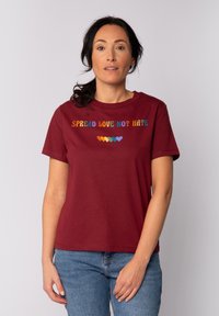 Bordeaux katoenen t-shirt met korte mouwen, met de tekst "SPREAD LOVE NOT HATE" in kleurrijke letters en een rij van veelkleurige harten.
