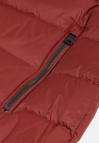 Roter Steppjackenabschnitt mit schwarzem Reißverschluss, gesteppter Textur und glattem synthetischem Material mit sichtbaren Nähdetails.