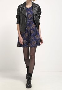 Black leather biker jacket over a navy floral dress. Dress features short sleeves, flared skirt, and floral pattern. Black tights and lace-up boots.