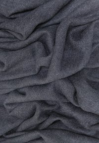 Ciemnoszary, miękki materiał o lekko puszystej teksturze, układający się w luźne fałdy, tworząc wrażenie głębi i ruchu.