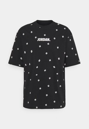 Czarny T-shirt z krótkim rękawem, z nadrukiem "JORDAN." w białym kolorze na piersi oraz małymi białymi prostokątnymi wzorami rozmieszczonymi na tkaninie.