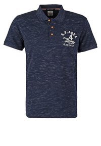 Marinblå pikétröja med korta ärmar, tillverkad av texturerat tyg. Har en knappslå med två knappar och ett vitt grafiskt tryck på bröstet.