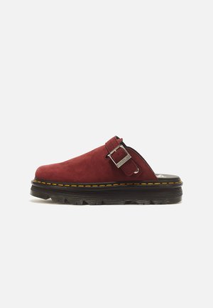 Punane seemisnahast slip-on king reguleeritava hõbedase pannlaga, musta paksu tallaga ja kollase õmbluse detailiga.