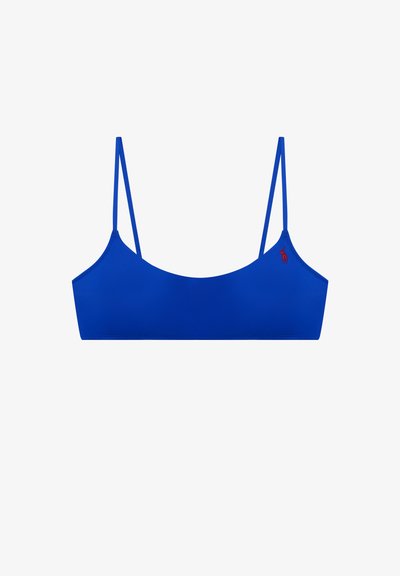 Μπλε σουτιέν bralette με λεπτές ρυθμιζόμενες τιράντες και μικρό κόκκινο κεντητό λογότυπο στην αριστερή πλευρά, εμφανίζεται σε απλό λευκό φόντο.