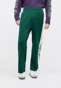 Πράσινο αθλητικό παντελόνι από λείο ύφασμα, με λευκές πλευρικές ρίγες, κεντημένο λογότυπο και άνετη γραμμή με ελαστική μέση.