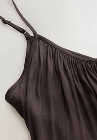 Haut sans manches marron foncé avec bretelles fines réglables et détail de tissu froncé le long de l'encolure sur un fond clair.