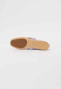 Lilac slip-on kurpes ar gludu ādas virsu, bizēm dekorēts un platu tumši brūnu gumijas zoli ar rakstainu protektoru.