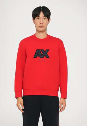 Czerwona bawełniana bluza z teksturowanym czarnym logo "AX" oraz napisem "Armani Exchange". Długie rękawy z prążkowanymi mankietami, klasyczny okrągły dekolt.