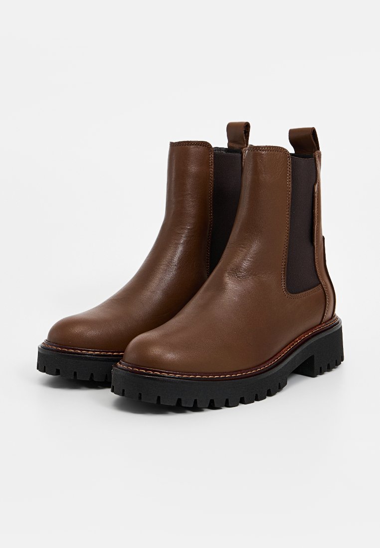 Braune Leder-Stiefeletten mit elastischen Seiteneinsätzen, chunkiger schwarzer Gummisohle und kontrastierenden Nähten. Langlebiges und einfach anzuziehendendes Design.