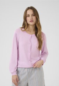 Light pink cardigan sweater with long sleeves and a round neck, featuring a button-down front and soft, smooth texture.