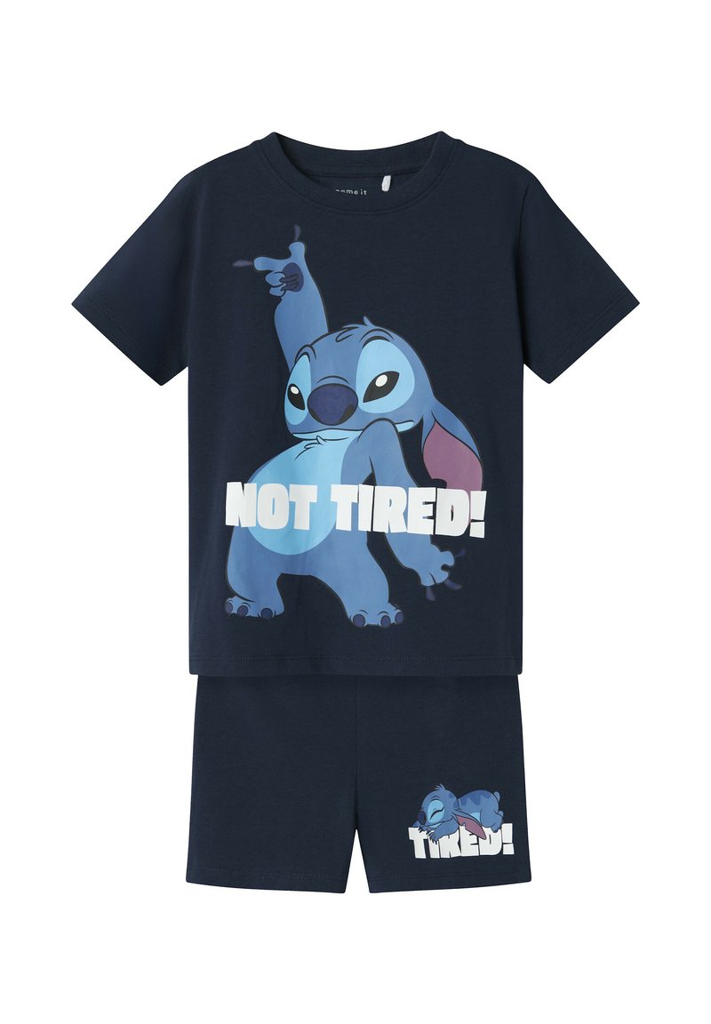 Marineblauw kinderpyjama set met Stitch-personage; het shirt toont Stitch poseert met de tekst "NIET MOE!", de korte broek toont slapende Stitch met de tekst "MOE!".