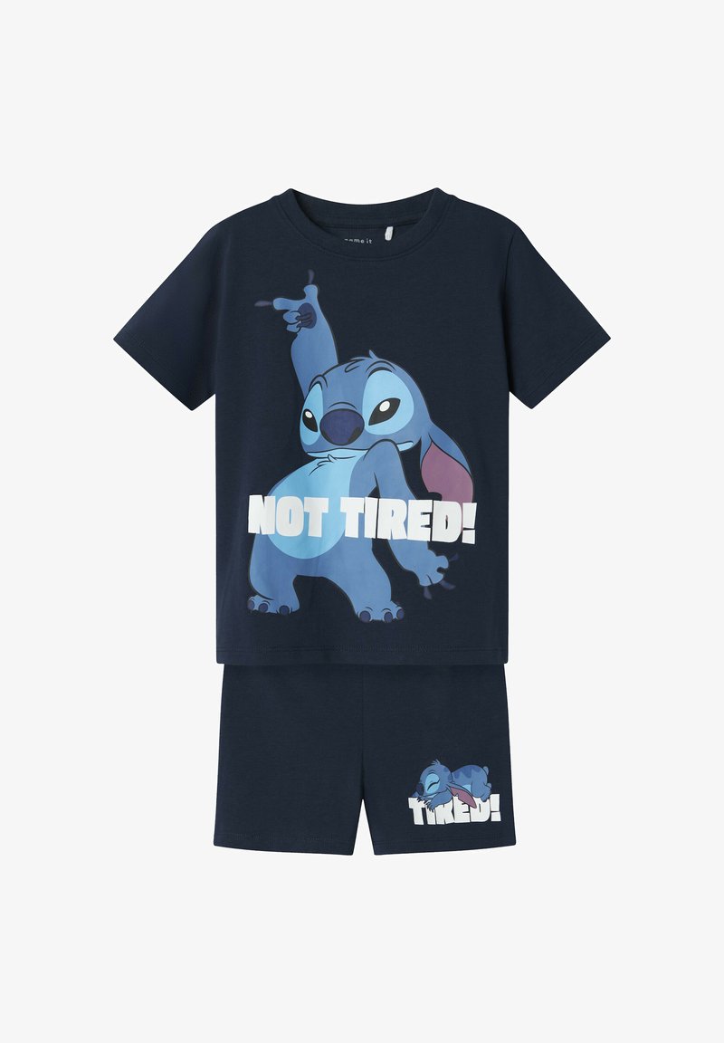 Marineblauw kinderpyjama set met Stitch-personage; het shirt toont Stitch poseert met de tekst "NIET MOE!", de korte broek toont slapende Stitch met de tekst "MOE!".