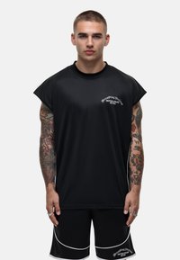 Zwarte sportieve t-shirt met korte mouwen en ronde halslijn, voorzien van witte logo-tekst en een losse pasvorm. Gekoppeld aan zwarte shorts met witte piping.