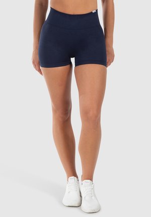 Donkerblauwe high-waisted shorts met een gladde textuur en een elastische tailleband, gecombineerd met witte sportieve schoenen.