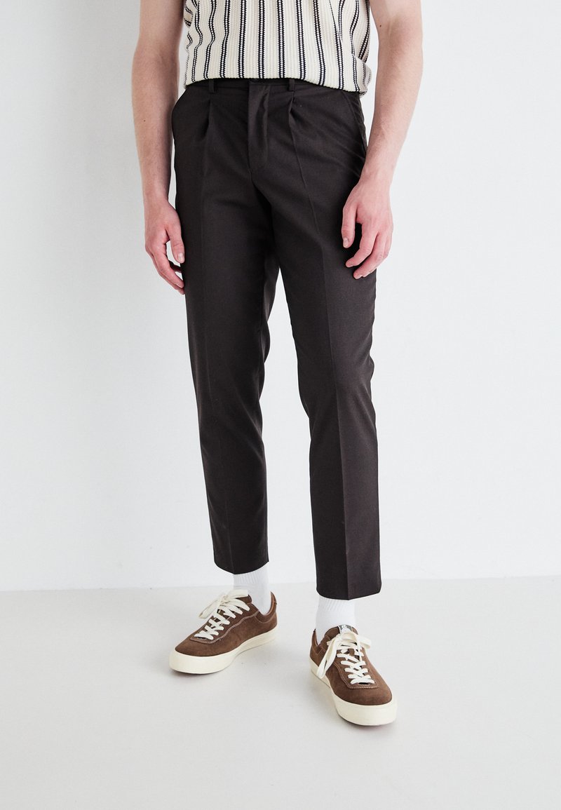 Temno rjave krojene hlače slim fit, z naborki, stranskimi žepki in v kombinaciji z rjavimi in belimi supergami.