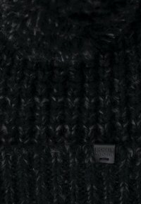 Czarna dziana czapka z miękkiej wełny, z teksturowanym wzorem. Na boku widoczna jest mała skórzana metka z napisem "Bickley + Mitchell".