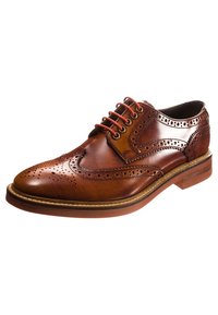 Chaussure à bout fleuri en cuir marron avec des détails de conception perforés, des lacets rouges et une semelle marron robuste. Surface lisse et finition polie.