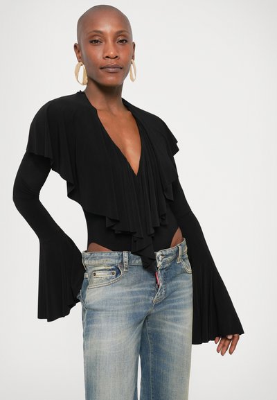 Μαύρο κορμάκι με στρώσεις βολάν, βαθύ V ντεκολτέ και μακριά φαρδιά μανίκια, συνδυασμένο με ανοιχτό μπλε τζιν παντελόνι. Απλός σχεδιασμός και λεία υφή.