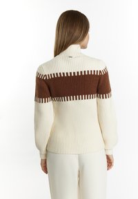 Maglione lavorato a maglia in crema e marrone, con colletto alto, texture a costine e un audace motivo a blocchi di colore sul retro.