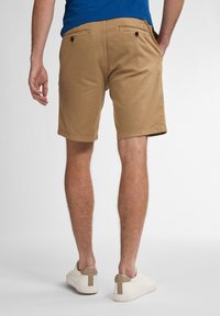 Khaki shorts lavet af bomuld, med baglommer med knapper, flad front og en skræddersyet pasform. Båret med hvide sneakers.