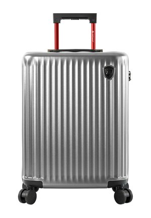 Silver hard-shell suitcase with vertical ridges, black base wheels, and an extended red telescopic handle.