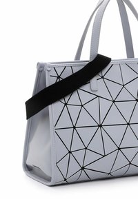 Ljust grå handväska tillverkad av glansigt material, med ett geometriskt svart mönster. Den har två handtag och ett justerbart svart rem.