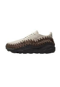 Sneakers med en beige vävd textilöverdel, mörkbruna detaljer och en svart gummisula; har flätad textur och snörning.