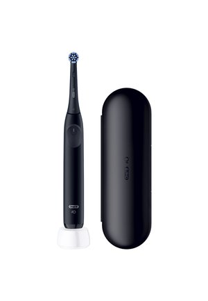 Brosse à dents électrique noire avec tête ronde sur chargeur blanc à côté d’un étui de voyage noir assorti sur fond blanc.