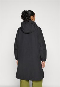 Zwarte waterdichte jas met capuchon, voorzien van elastische manchetten en een iets langere achterkant. Glad textuur en minimalistisch ontwerp.