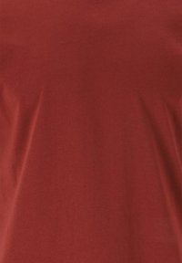 Röd bomullströja med mjuk textur, med en enkel design och slät yta utan några synliga mönster eller detaljer.