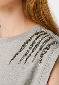 Hallatav hall ilma varrukatena särk, millel on dekoratiivsed helmedega mustrid õlgadel. Kangas tundub pehme ja rannetega, õrn kaelus.