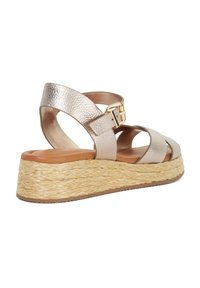 Metalen gouden wedge sandaal met gevlochten jute platform, verstelbare enkelgesp en kruisbanden, met een soepele leren textuur.
